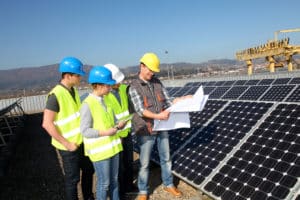 Group of men and women in hard hats with solar panels