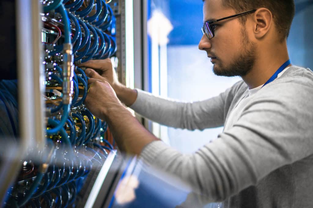 man checking cables in wiring cabinet