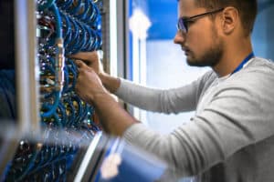 man connecting cables in wiring cabinet