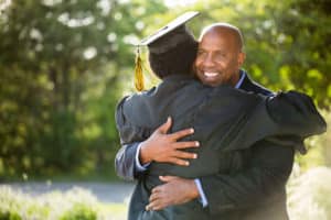 African American father and son embracing at graduation